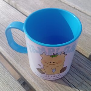 Vista lateral de la taza infantil de plástico azul con diseño de becerrito y texto “Pamplona, mi lugar favorito / Iruña nire lekurik gogokoena”, diseño exclusivo ButtiBou Pamplona. Side view of light blue plastic children’s mug with calf design and text “Pamplona, my favorite place / Iruña nire lekurik gogokoena”, exclusive ButtiBou Pamplona design.