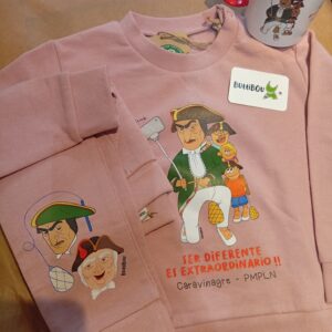 Detalle del conjunto infantil rosa de algodón orgánico con el kiliki Caravinagre y la frase “Ser diferente es extraordinario”. Detail of the pink organic cotton kids set featuring Caravinagre and the phrase “Being different is extraordinary.