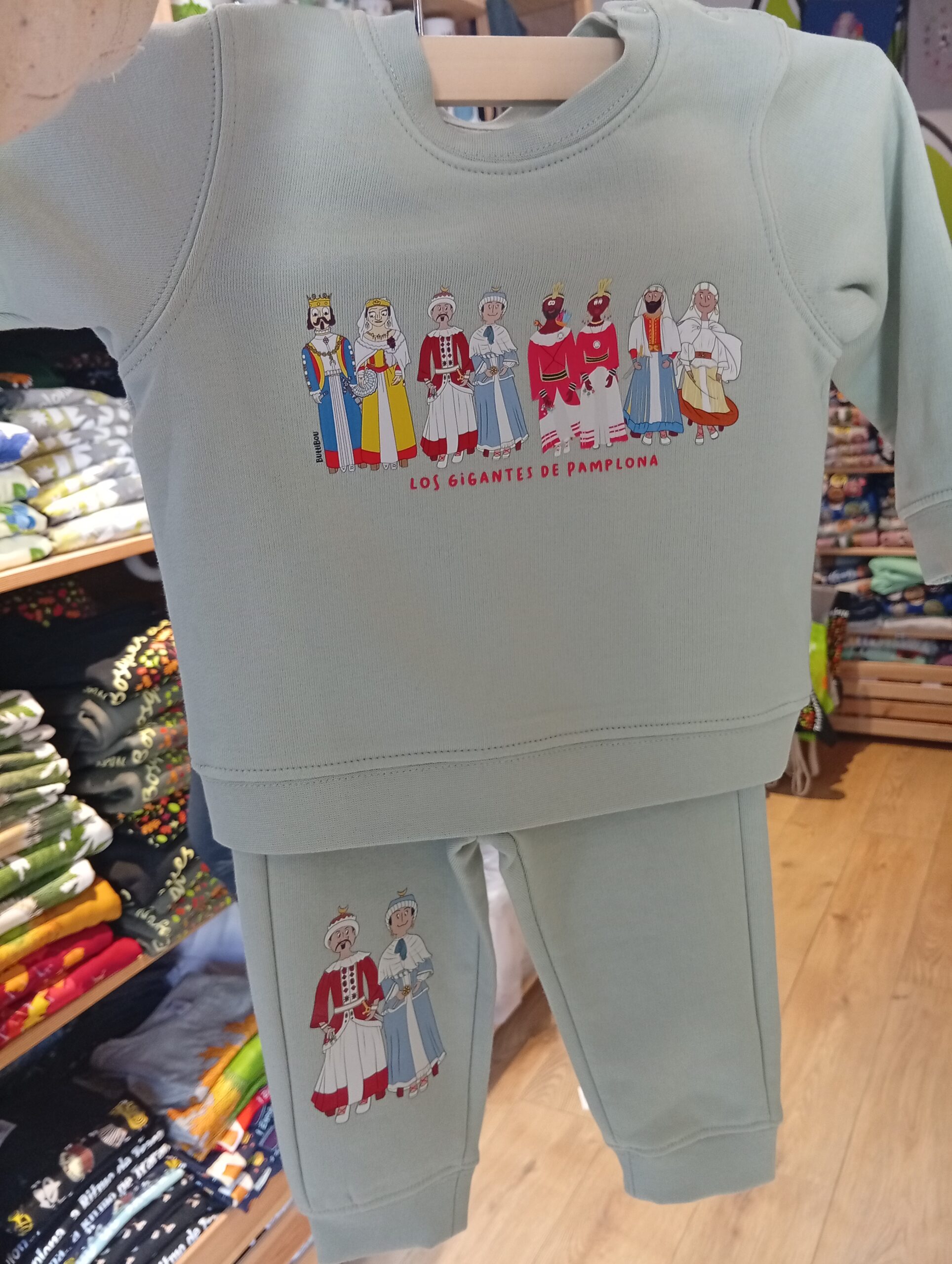 Conjunto de bebé con sudadera y pantalón verde de algodón orgánico Mini Arata & Selim-pia, inspirado en los gigantes de Pamplona. Diseño exclusivo de ButtiBou Pamplona. Mint green organic cotton baby set with sweatshirt and pants Mini Arata & Selim-pia, inspired by the giants of Pamplona. Exclusive ButtiBou Pamplona design. Conjunto de bebé con sudadera y pantalón de algodón orgánico Mini Arata & Selim-pia inspirado en los gigantes de Pamplona de ButtiBou Pamplona. Baby set with sweatshirt and pants in organic cotton Mini Arata & Selim-pia inspired by the giants of Pamplona by ButtiBou Pamplona