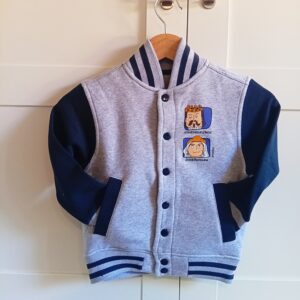 Vista frontal sudadera High School con interior gris claro, mangas azules, canalé bicolor y estampación “Gigantes JoseMiguelErico y JosePhamunda” en la parte delantera, diseño exclusivo ButtiBou Pamplona. Front view of High School sweatshirt with light gray interior, blue sleeves, bicolor ribbed collar, cuffs, and hem, and “Gigantes JoseMiguelErico and JosePhamunda” front print, exclusive ButtiBou Pamplona design.
