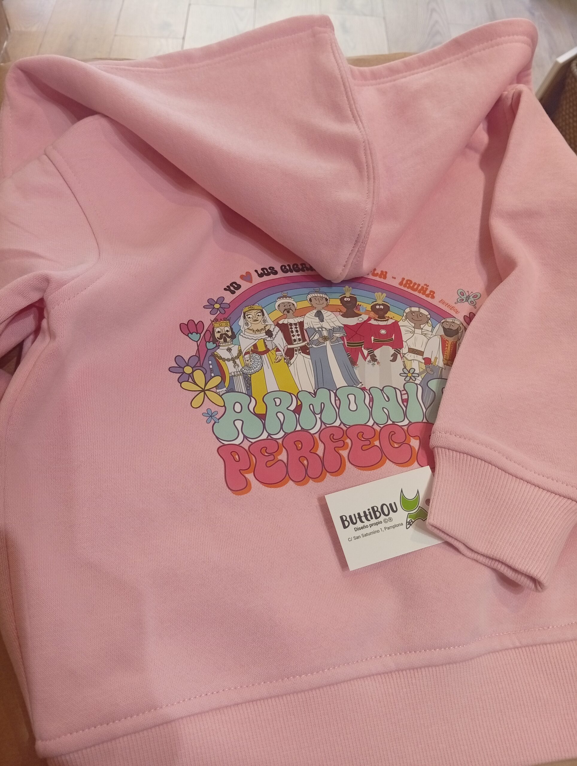 Los gigantes más queridos de Pamplona se unen en esta sudadera rosa con cremallera, llena de color, armonía y alegría.
Pamplona’s beloved giants come together in this pink zip-up hoodie, full of color, harmony, and joy. Sudadera infantil rosa con cremallera y capucha, diseño exclusivo “Gigantes en armonía” de ButtiBou Pamplona, inspirada en los gigantes de Pamplona. Pink children’s zip-up hoodie with hood, exclusive “Giants in Harmony” design by ButtiBou Pamplona, inspired by Pamplona’s giants.