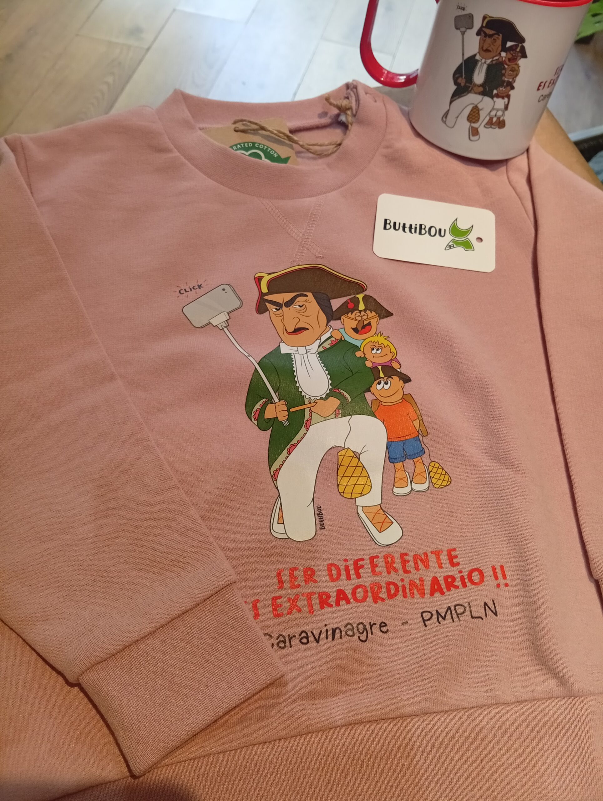 Sudadera rosa con el querido kiliki Caravinagre enseñando que ser diferente es extraordinario. Pink sweatshirt with Pamplona’s beloved Caravinagre kiliki teaching that being different is extraordinary. Sudadera infantil rosa con el kiliki Caravinagre y la frase “Ser diferente es extraordinario”, diseño exclusivo de ButtiBou Pamplona.Pink kids sweatshirt with Caravinagre design and the phrase “Being different is extraordinary”.