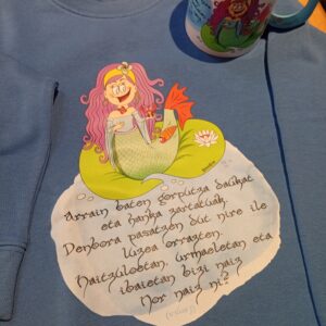 Sudadera infantil orgánica azul con diseño de una lamia, figura mitológica vasca, y una adivinanza en euskera. Blue organic kids sweatshirt with a design of a lamia, Basque mythological figure, and a riddle in Basque.